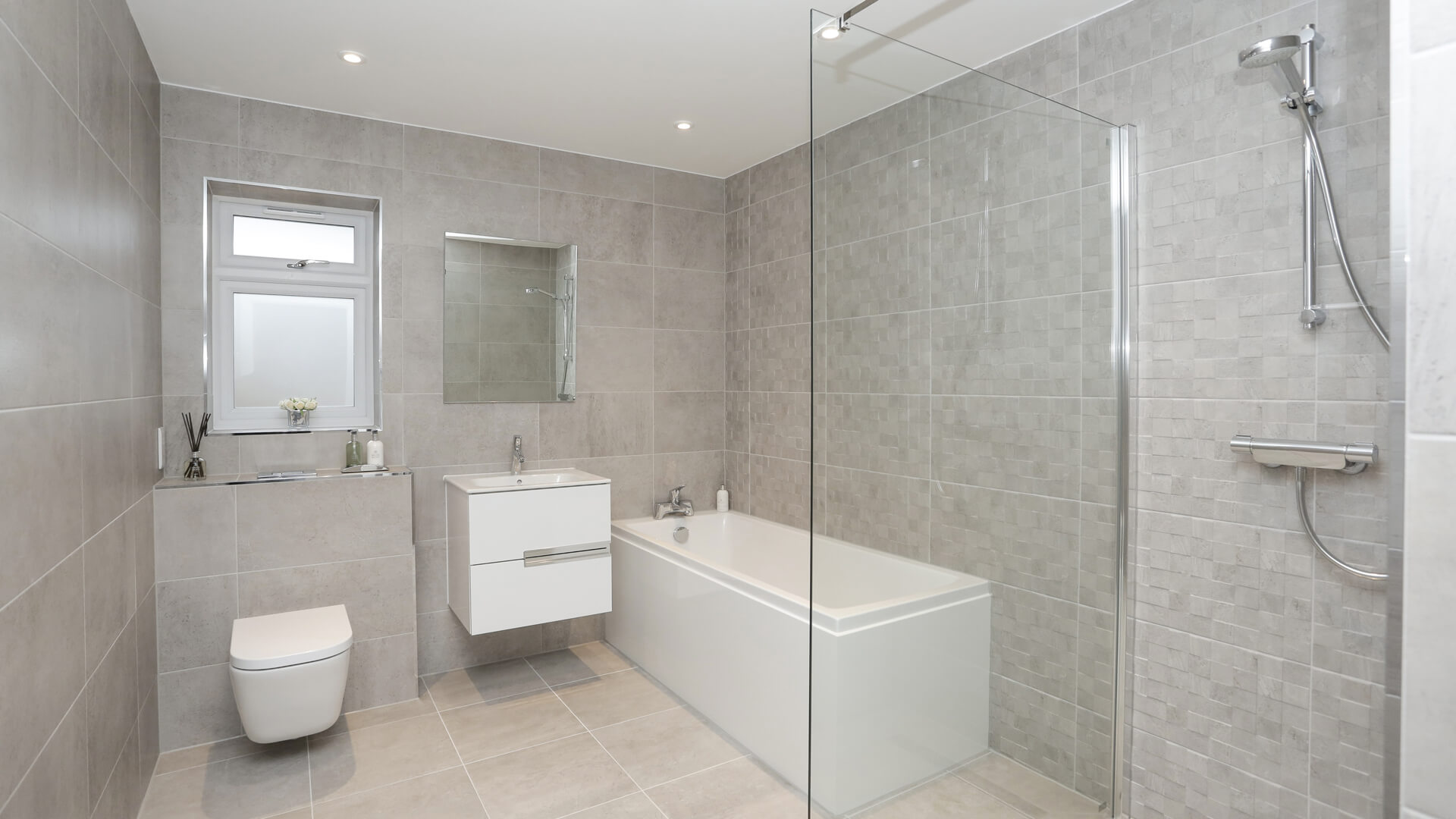 Bathroom with grey tiling, sink, toilet and bath