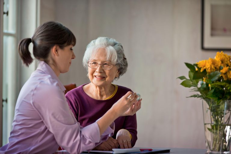 Senior woman talking with her caregiver about medication
