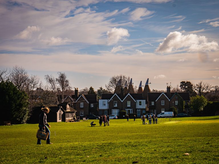 An open field at The Bearsted Green with families near a cricket green