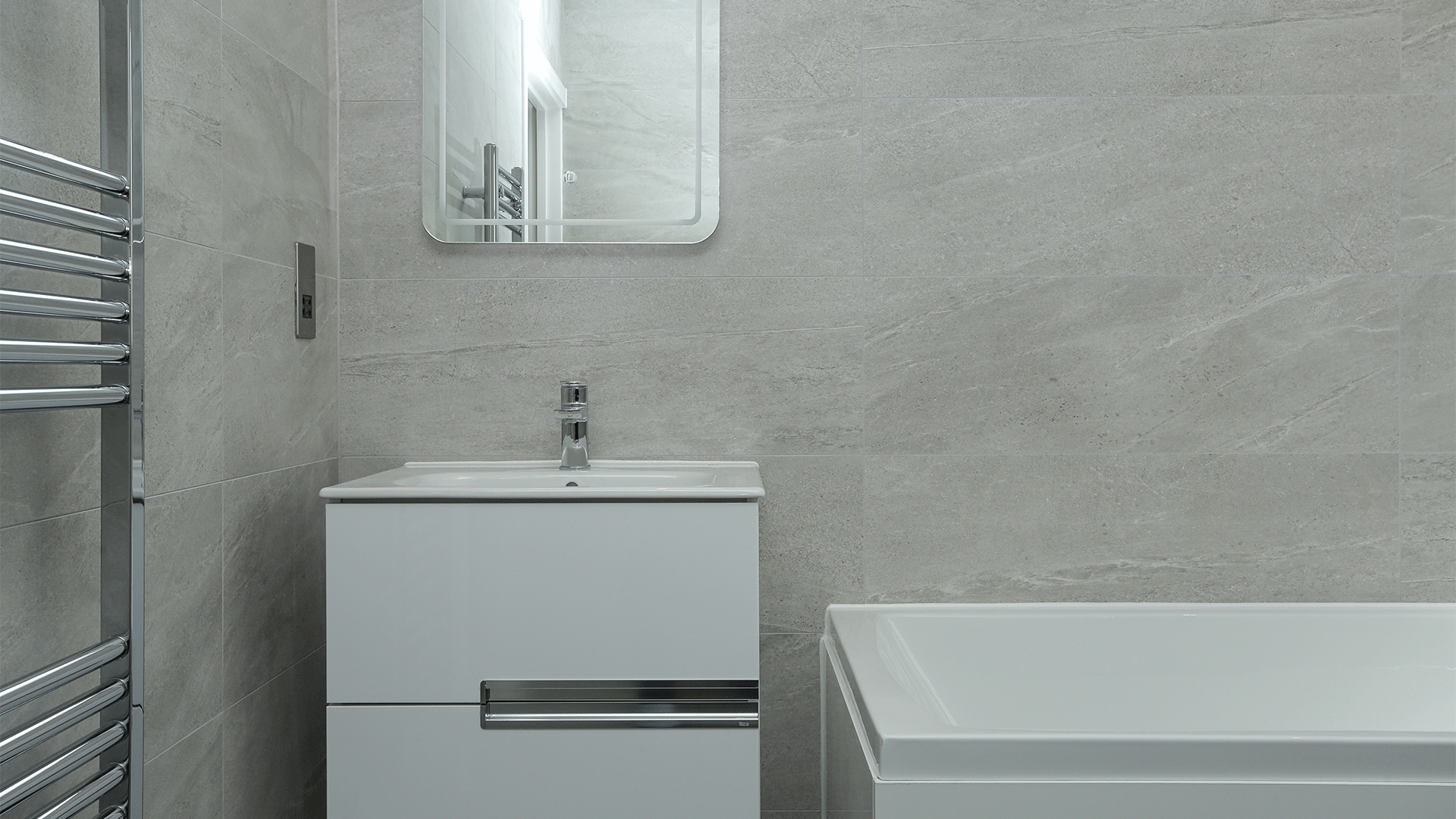 Sink basin with mirror next to a bath and towel rail at Miller's Meadow