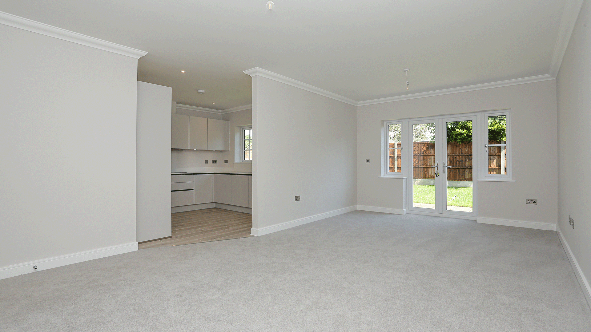 New build bungalow living room with grey carpet and open plan access to kitchen at Miller's Meadow plot 11