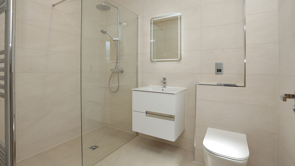 Beige tiled bathroom with shower, toilet, bath and sink basin with mirror at Miller's Meadow