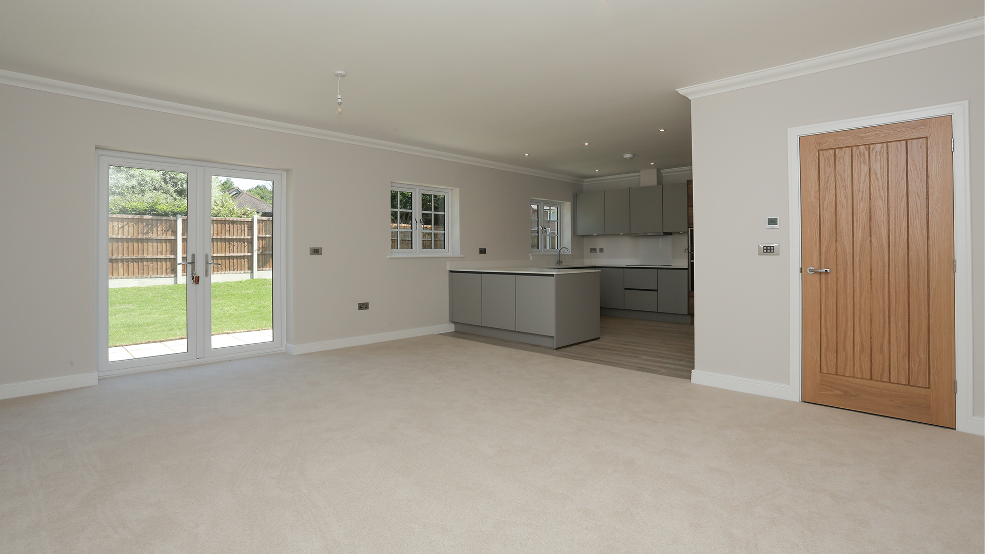 New build bungalow living room with beige carpet and access to open plan kitchen at Miller's Meadow plot 9