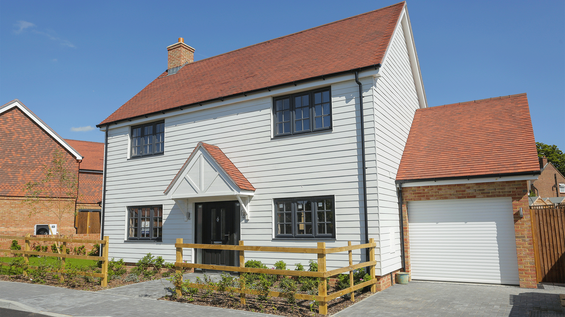 Miller's Meadow - Plot 7 featuring a large white detached house and garage on a sunny road