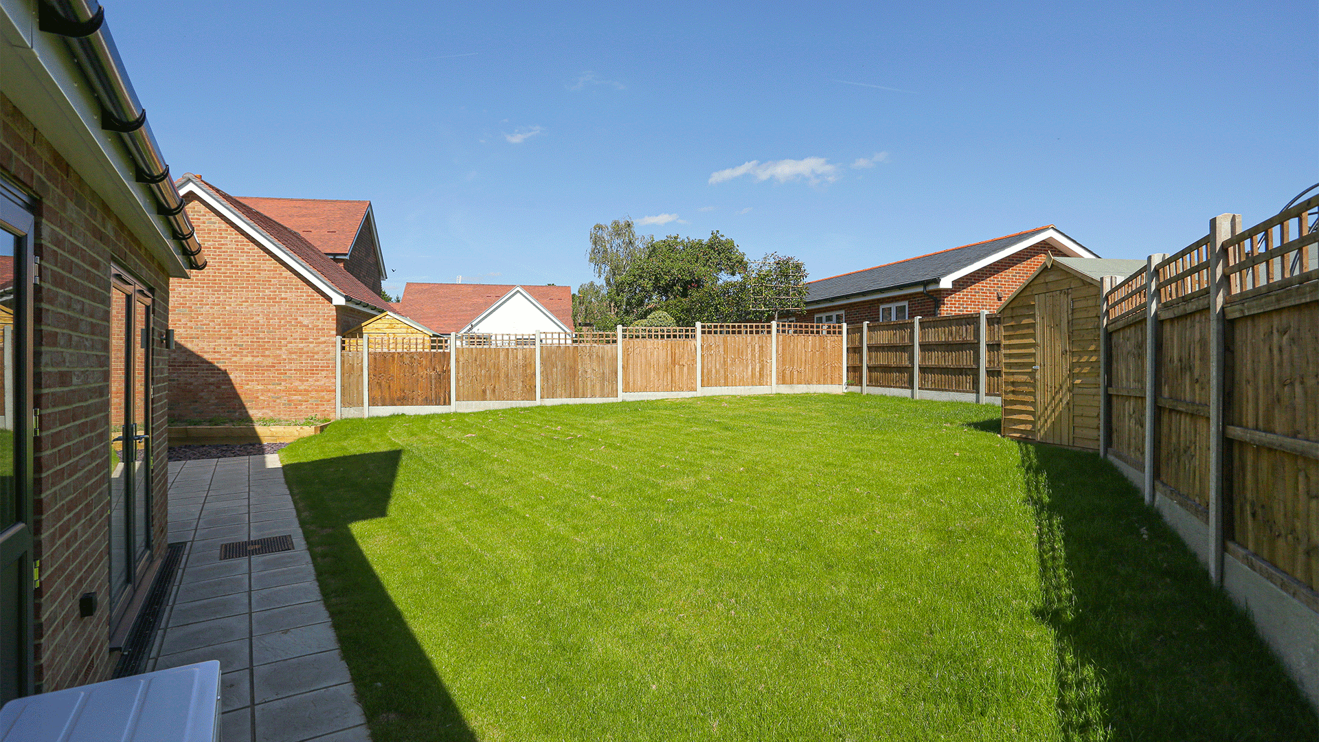 Miller's Meadow - Plot 7 Garden, a bright green turf with a pathway on the left and shed on the right