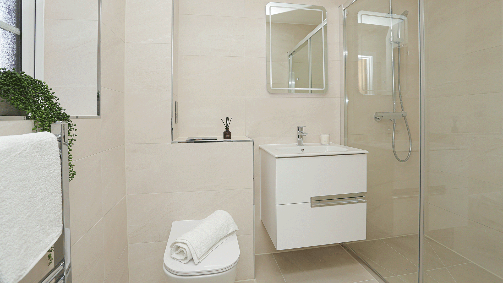 Tiled ensuite at plot 8 Miller's Meadow, with toilet, enclosed shower, sink basin, potted plant and mirror