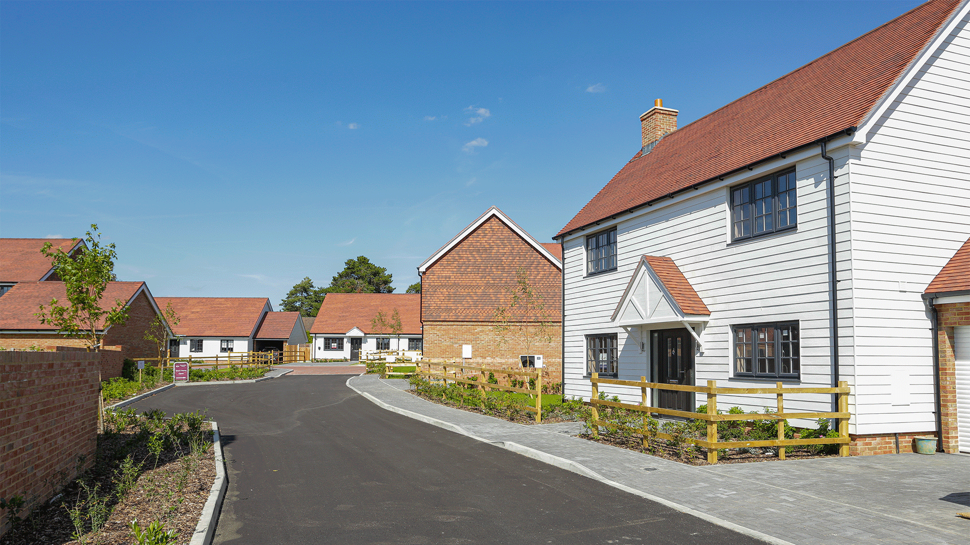 Miller's Meadow Street View featuring a large white detached house and facing down a sunny road