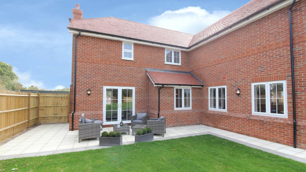 Rear garden with patio and outdoor rattan furniture.