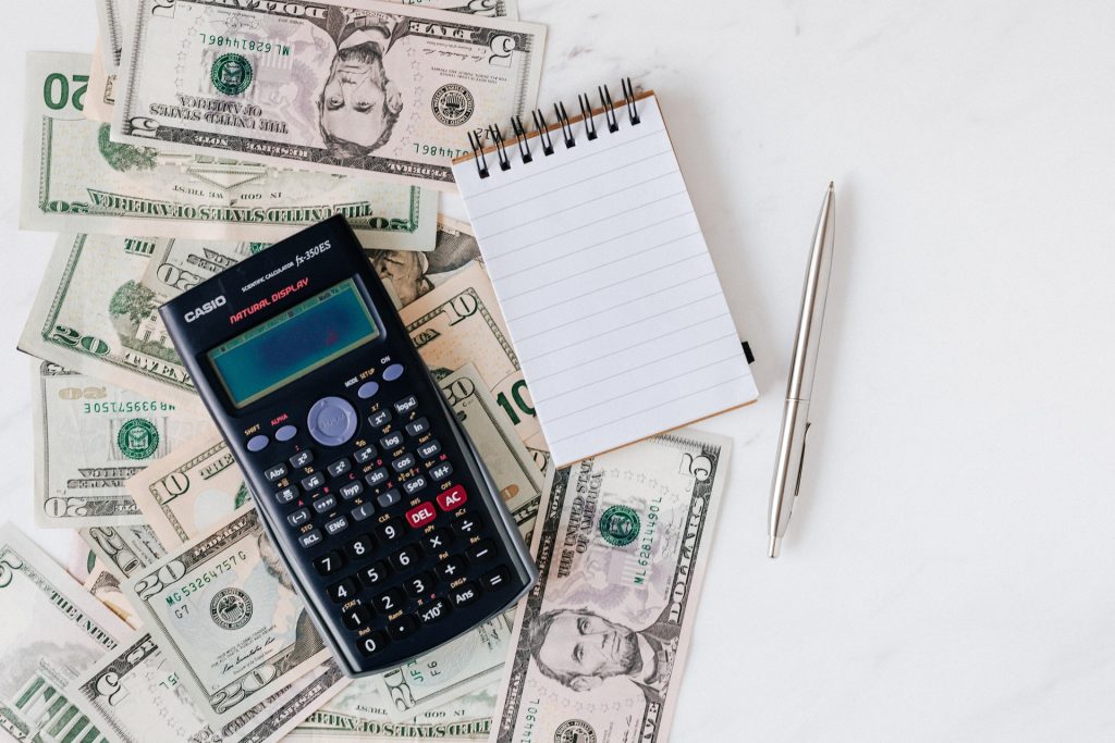 Calculator with notepad, pen and money behind