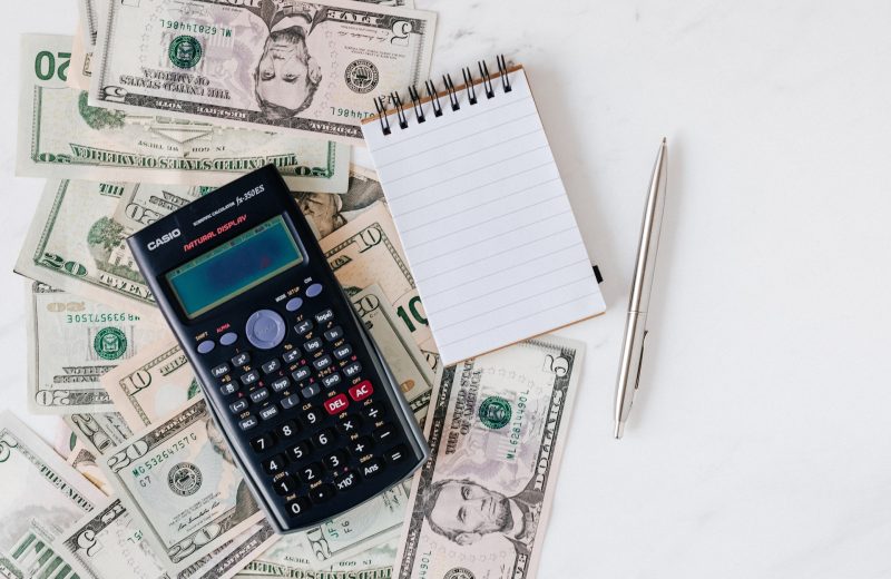 Calculator with notepad, pen and money behind