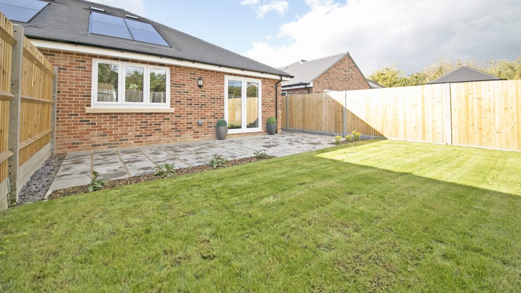 Bungalow rear view with laid lawn and patio.