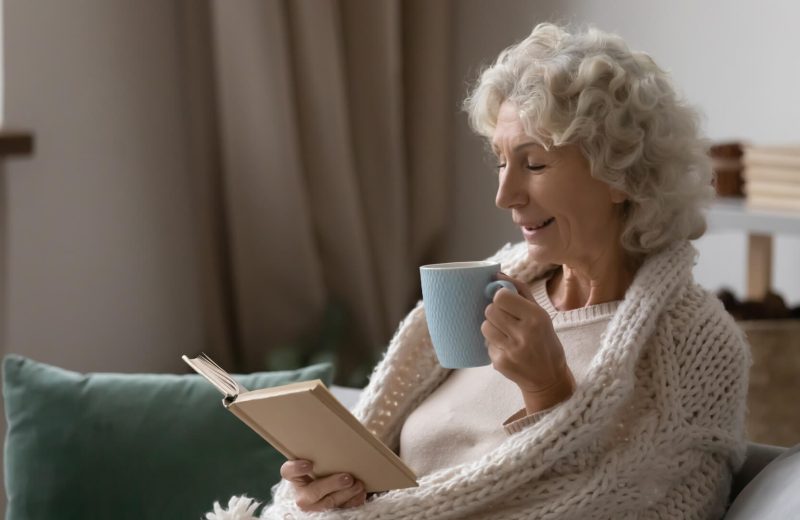 Elderly woman reading and drinking tea