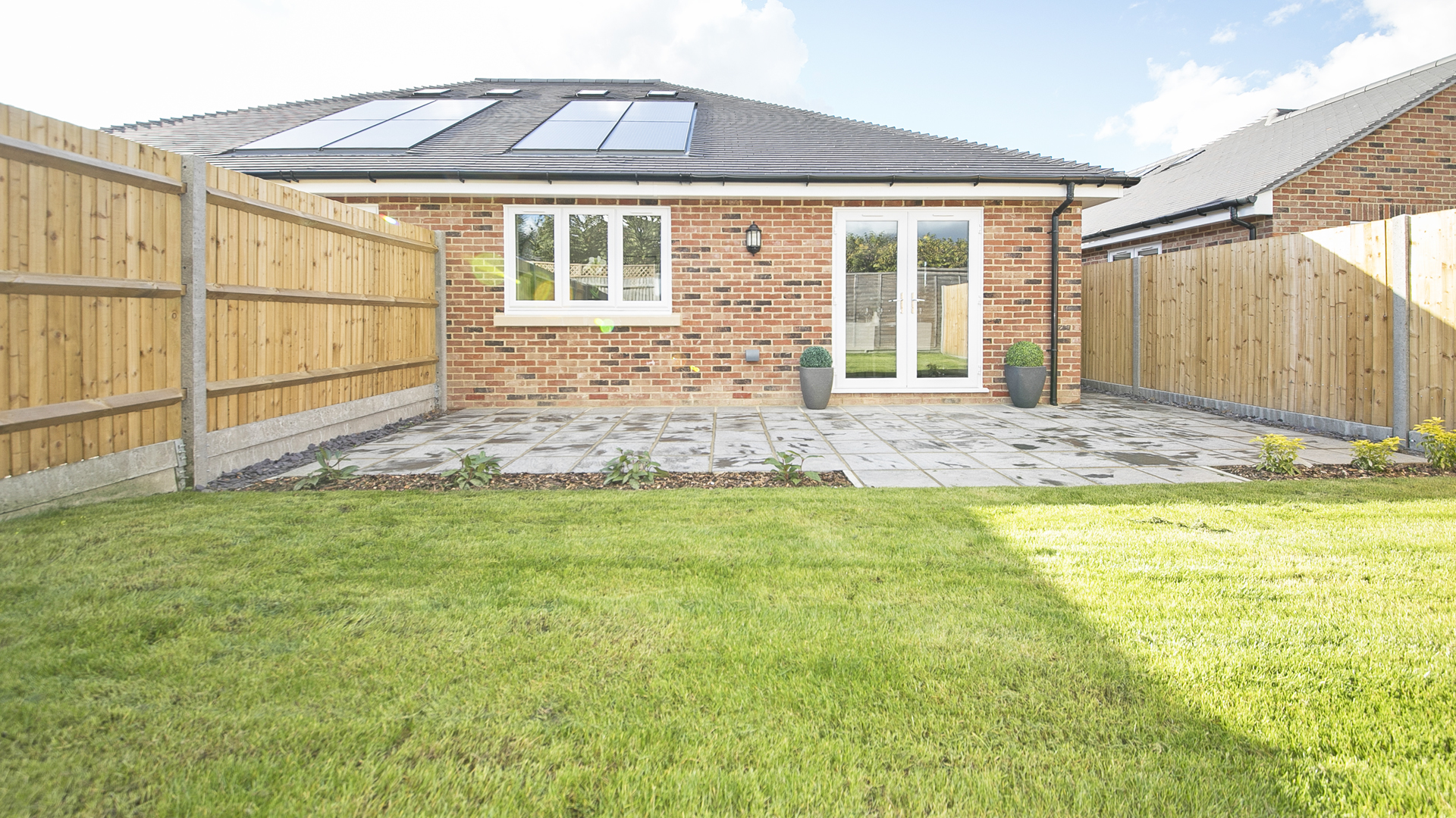 A new build bungalow at Churchfields, with grass and flower beds.