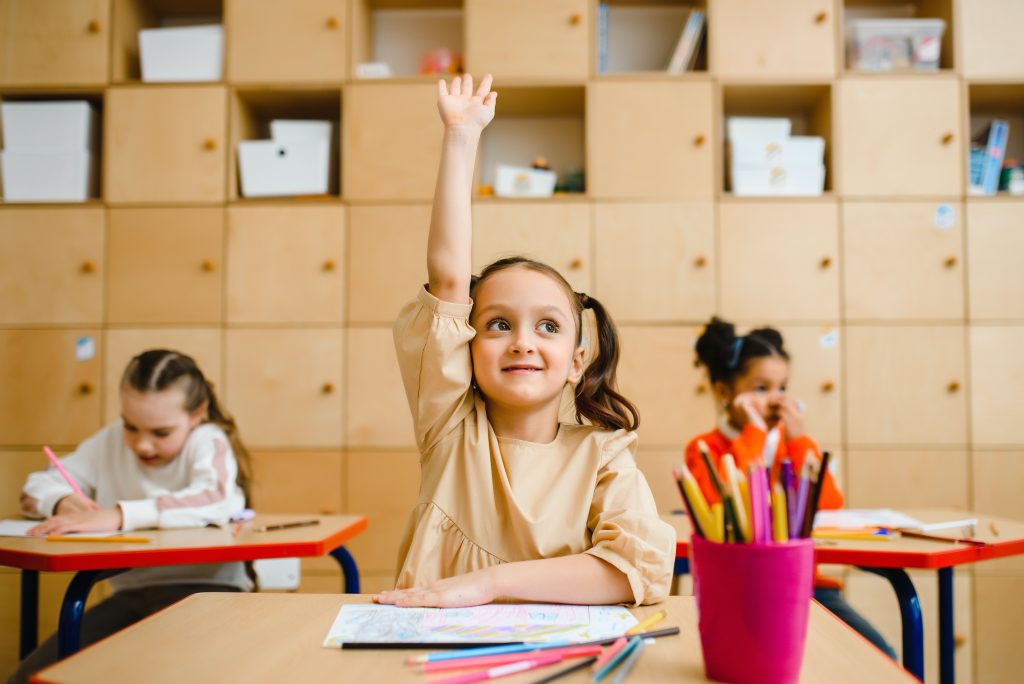Girl with hand up in the classroom