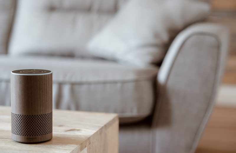 Amazon Alexa on a living room table with a grey sofa behind