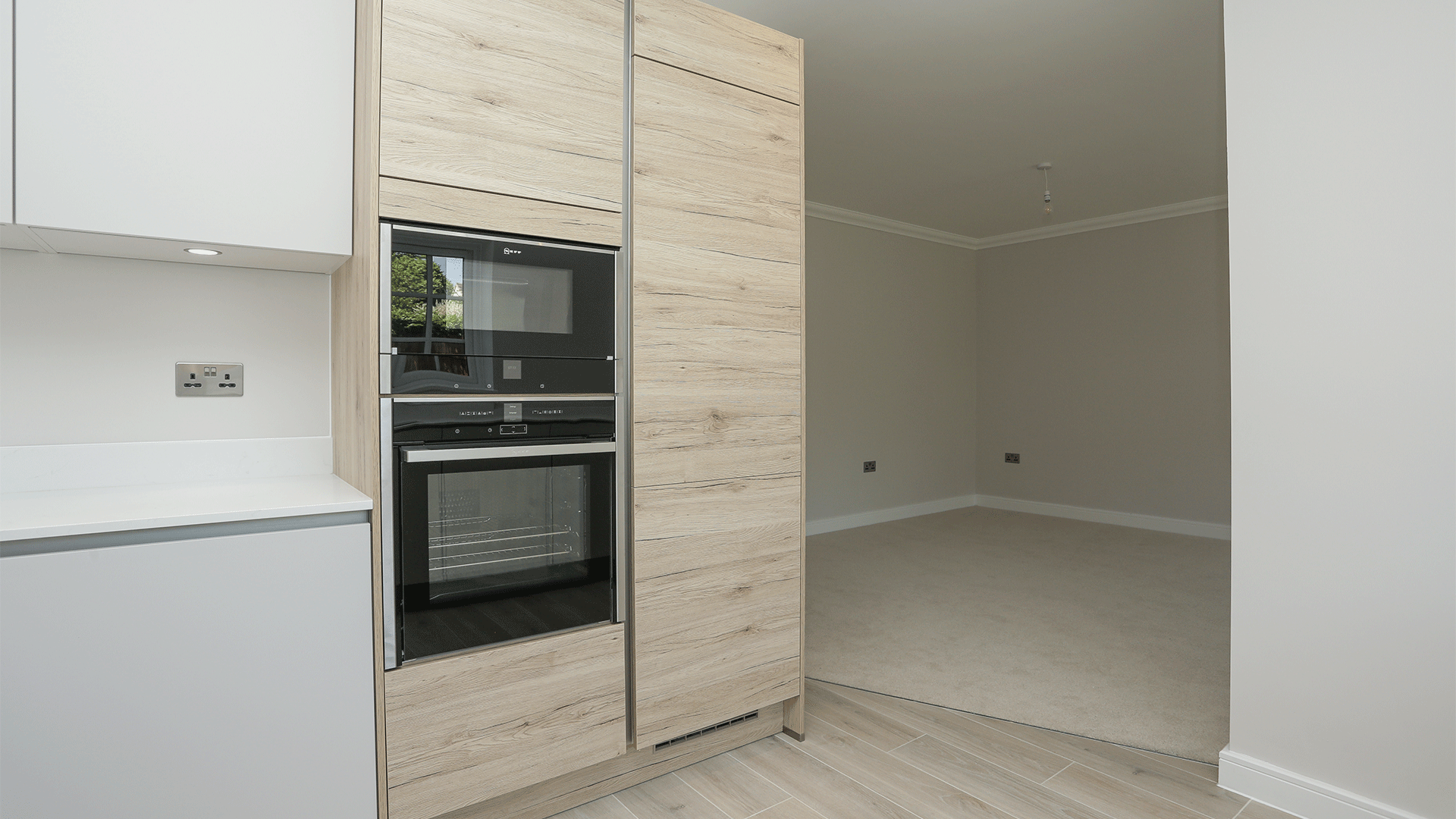 Wood effect wardrobes with integrated Neff oven appliance at Miller's Meadow plot 10 kitchen