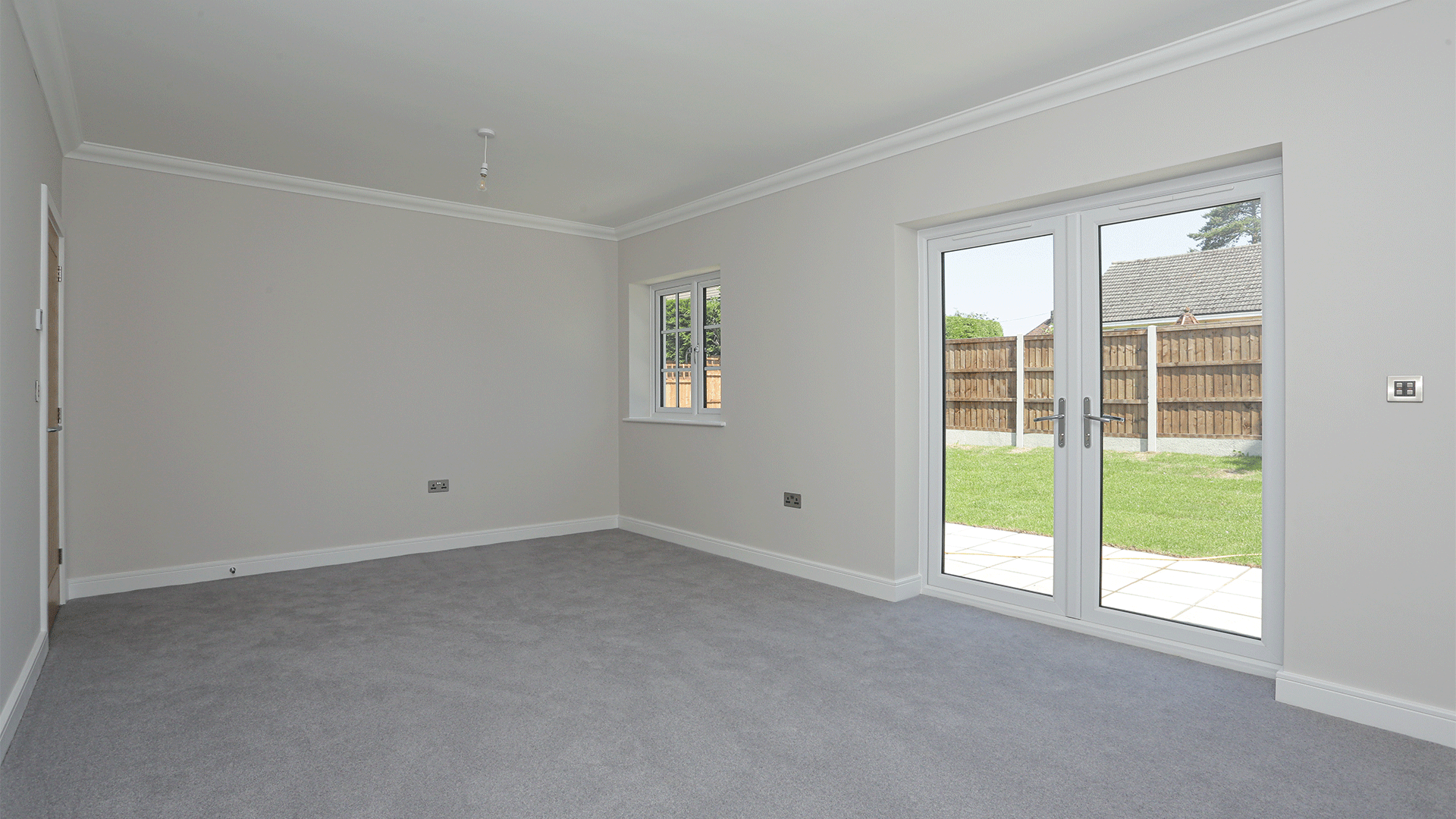 New build bungalow living room with grey carpet and double doors at Miller's Meadow plot 12