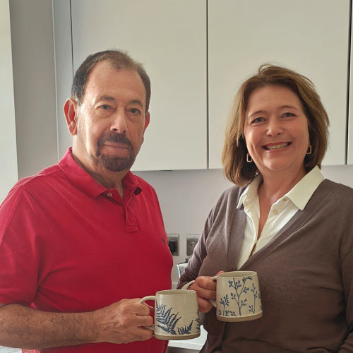 Happy new customers standing inside their new bungalow home at Miller's Meadow with a cup of tea
