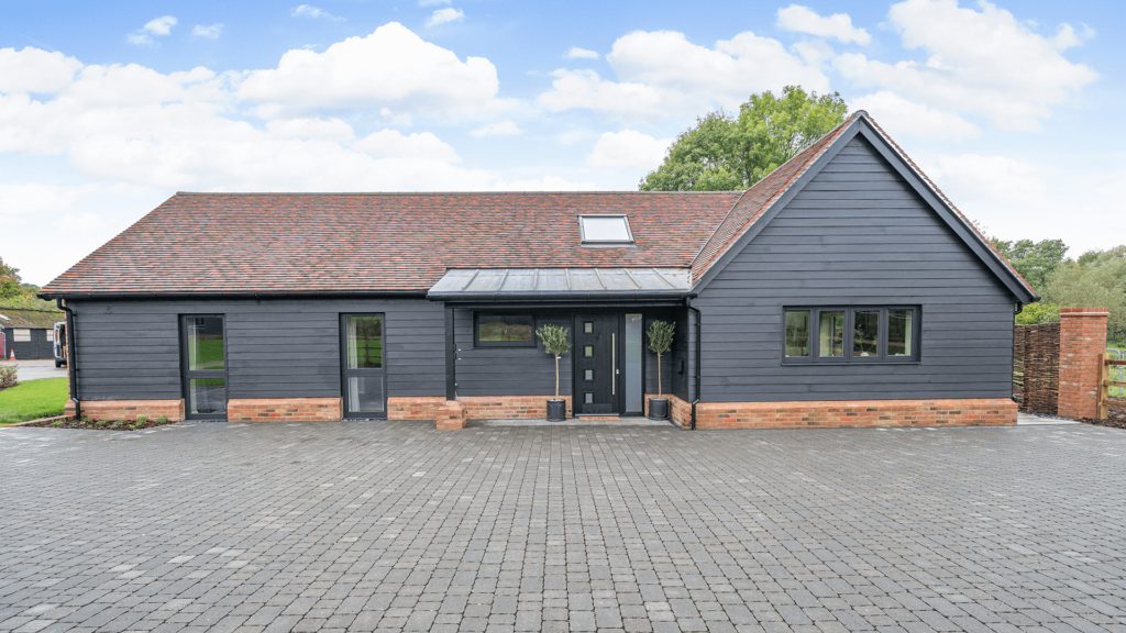 An external shot of plot 2, the bungalow has black wood slats and orange bricks along the bottom of the walls.