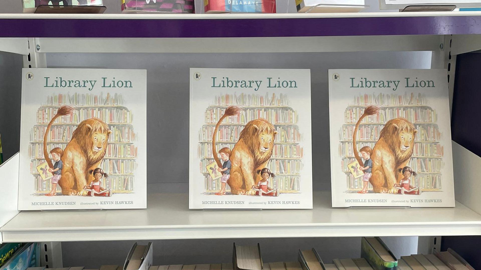 Three copies of the children's book The Library Lion sit next to each other on a library shelf.