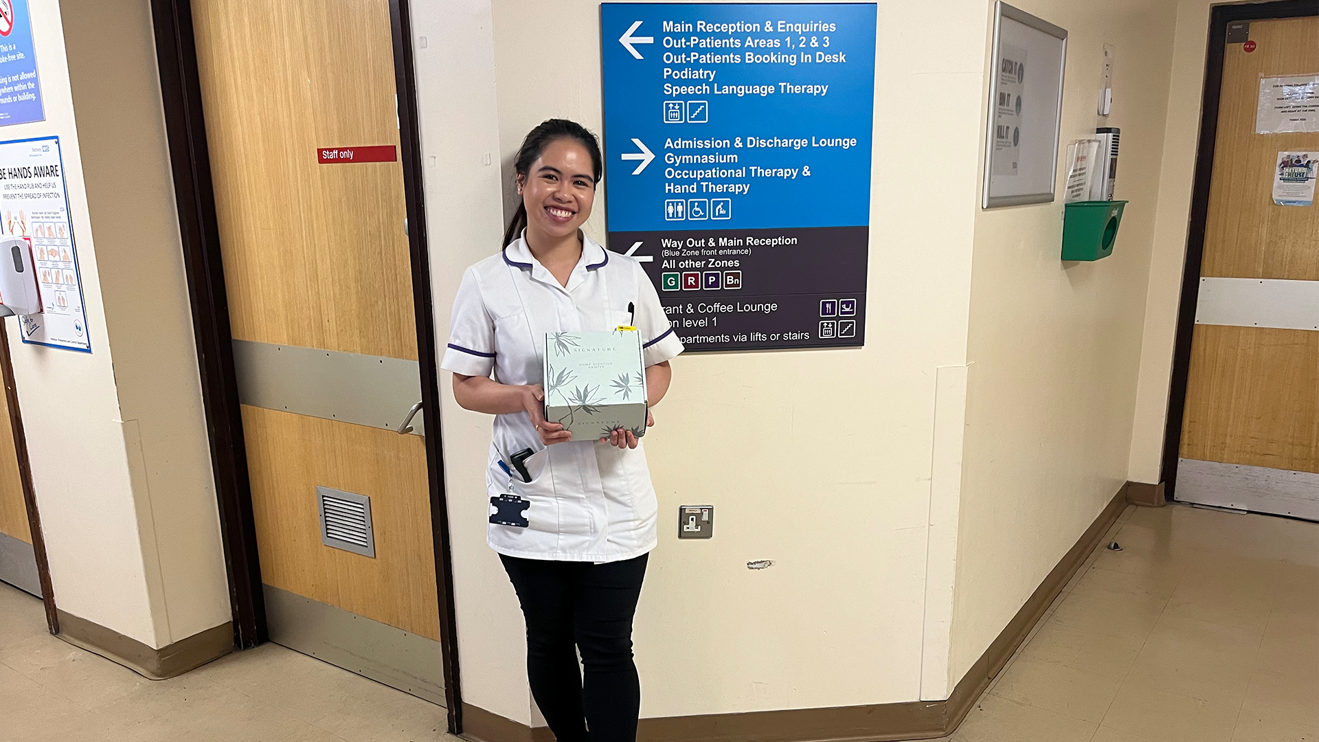 Nurse at Medway Maritime hospital stands in front of a sign holding a hamper that has been gifted