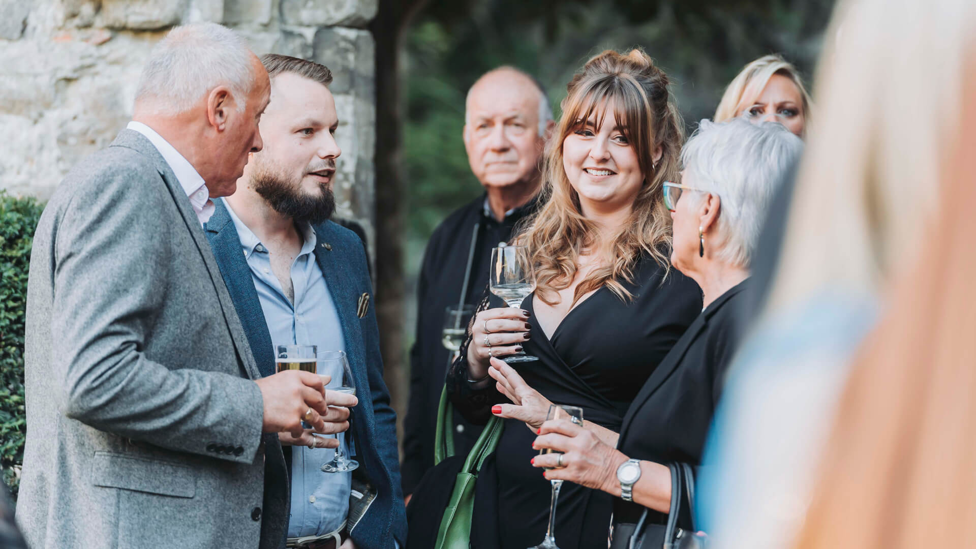 a group of people talking outside at a party holding drinks