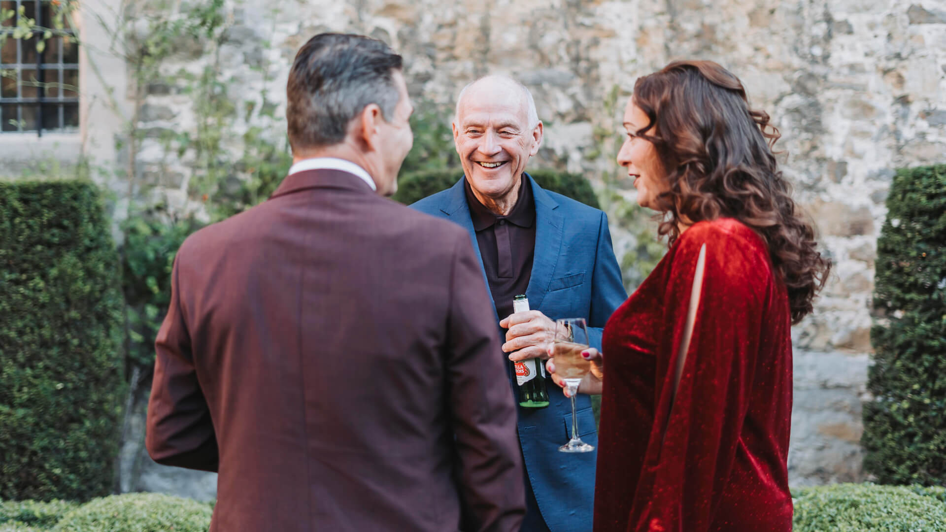 three people talking outside holding drinks