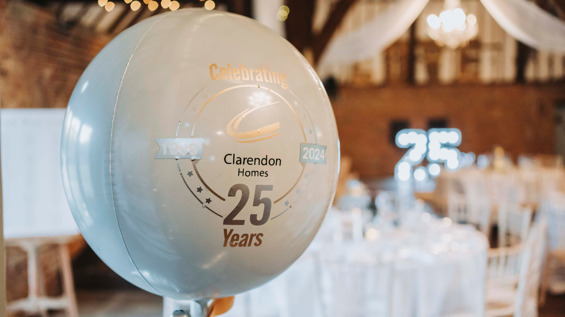 white balloon with logo on it, and with dinner tables and light up 25 numbers in the background