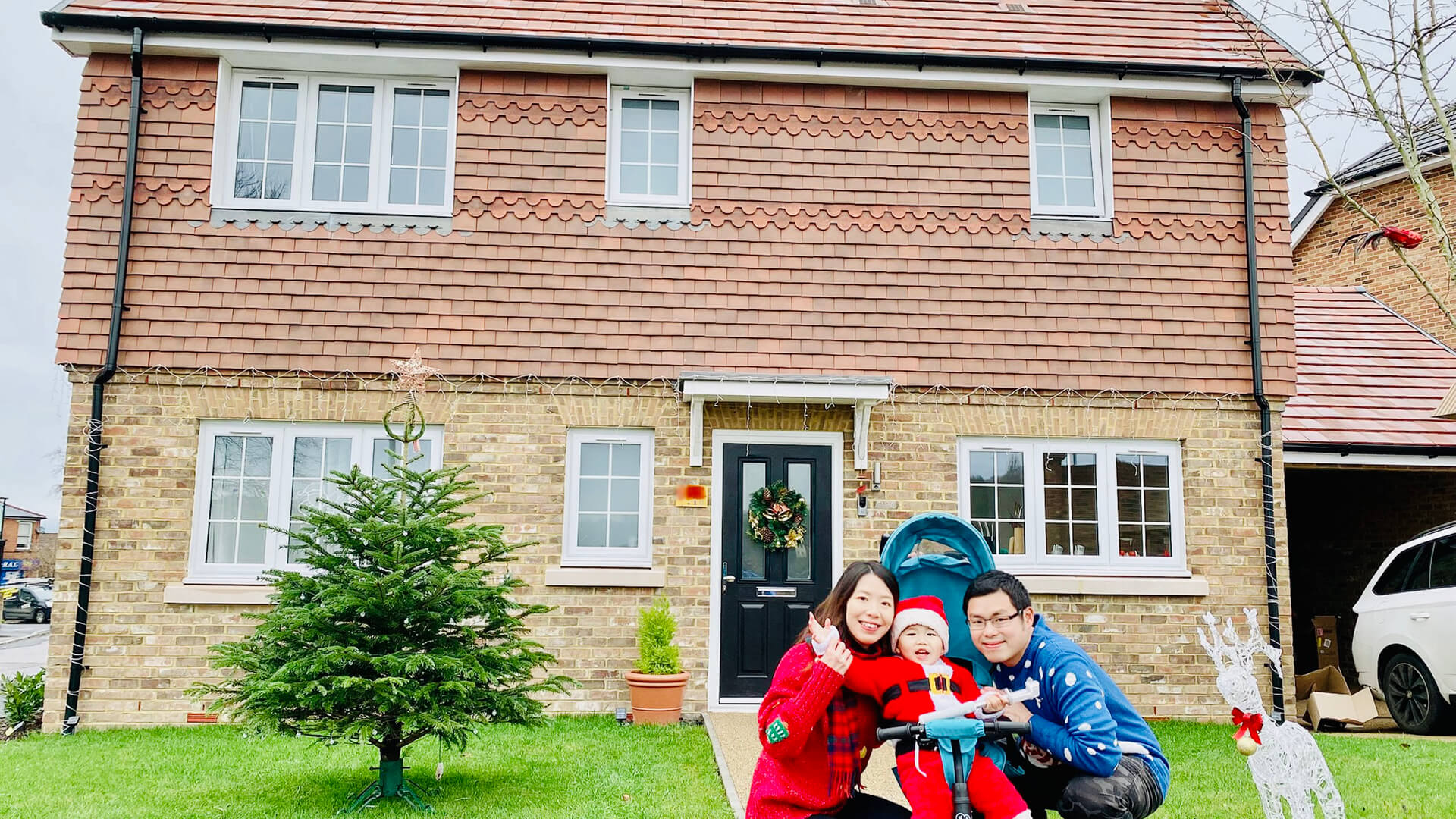 A family posing for a photo outside their house decorated for Christmas