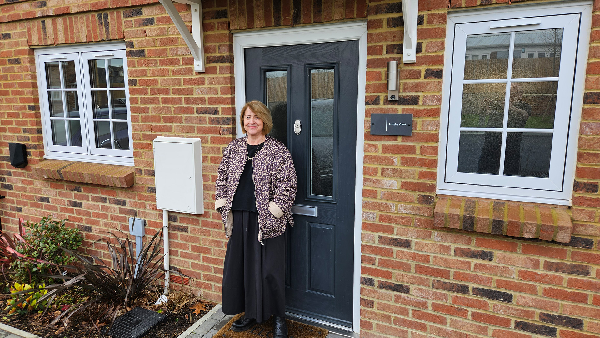 Woman posing for a photo outside a black front door