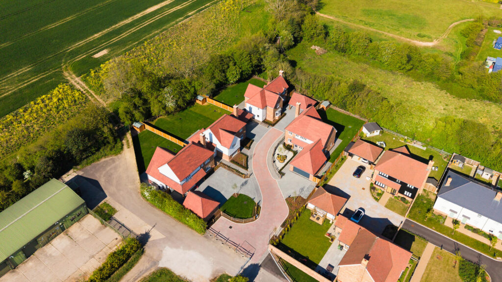 An aerial shot of The Chimes development with green fields surrounding it and houses on the right side.  