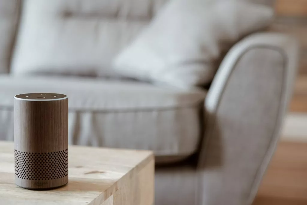 Amazon Alexa on a living room table with a grey sofa behind
