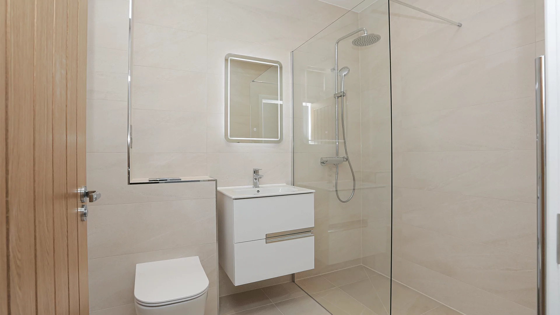 Tiled bathroom with shower, toilet and sink basin with mirror at Miller's Meadow.
