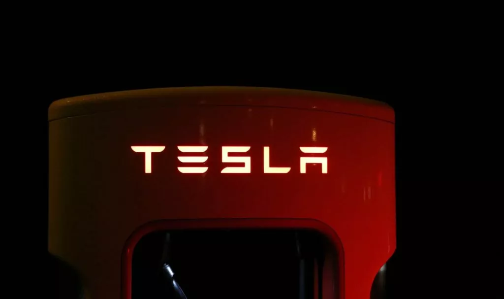 A  red tesla car charger in the dark with the text logo lit up 